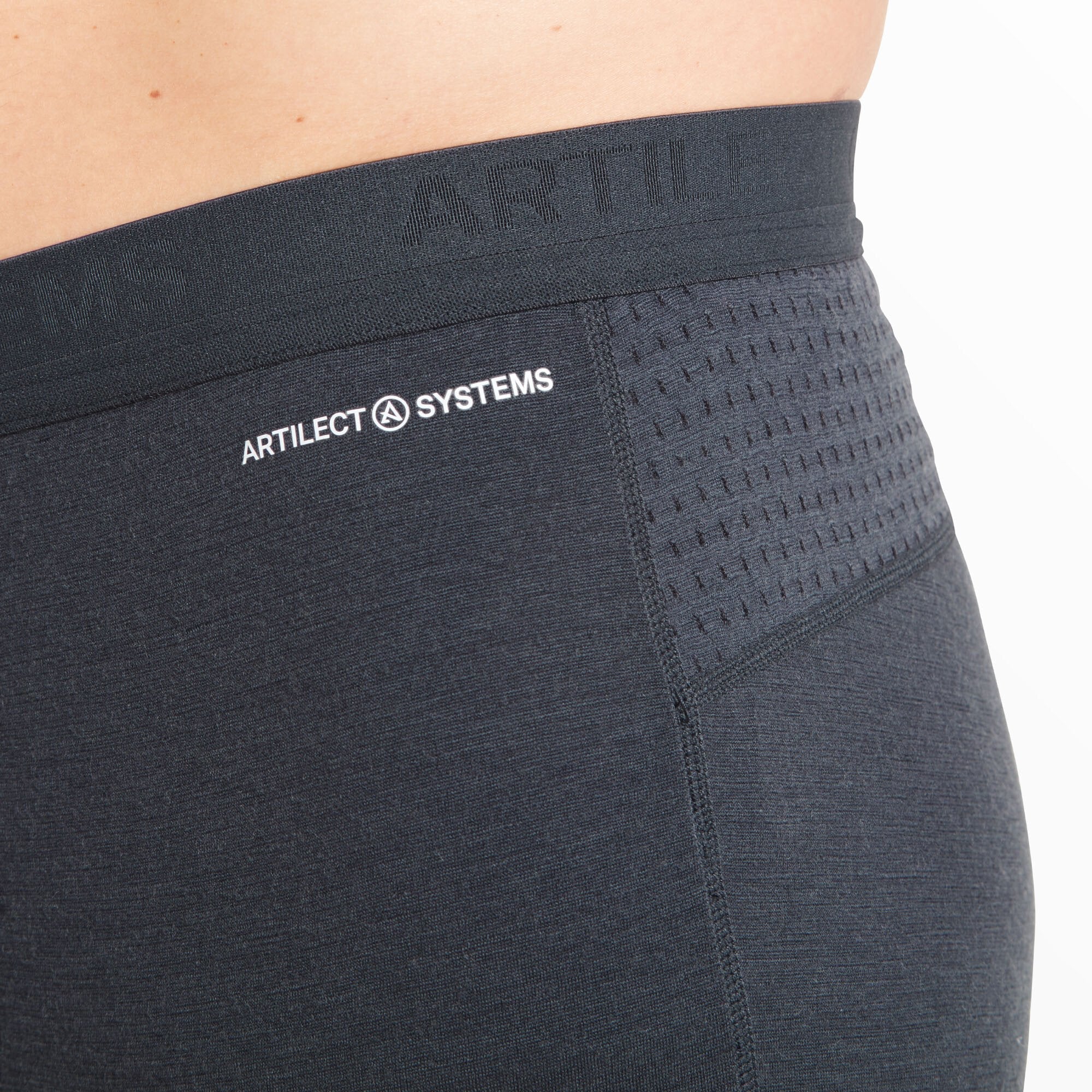 A close-up shot of the waistband area on the left side shows the "ARTILECT SYSTEMS" logo printed in white on the Artilect Performance Mens Boulder 125 3/4 Legging Blue. The perforated mesh detailing is clearly visible, designed for ventilation, and the texture of the stretch fabric is evident, emphasizing flexibility and performance.