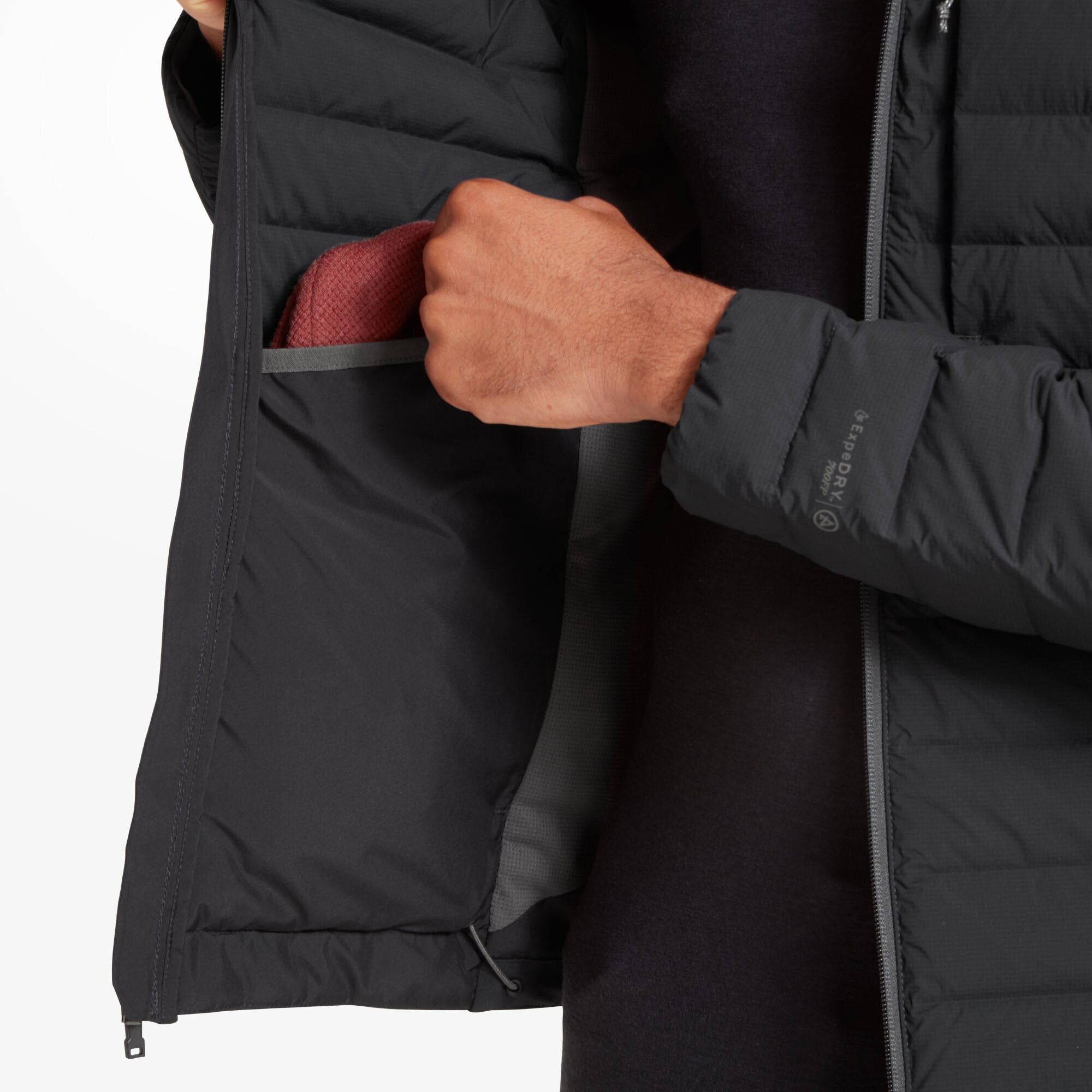 Image showing the inside of the Artilect Performance Mens Divide Fusion Stretch Hoodie Black. The model holds the jacket open, revealing a mesh interior lining and a deep internal drop pocket containing a red fabric item. The inner hem includes an adjustable drawcord.
