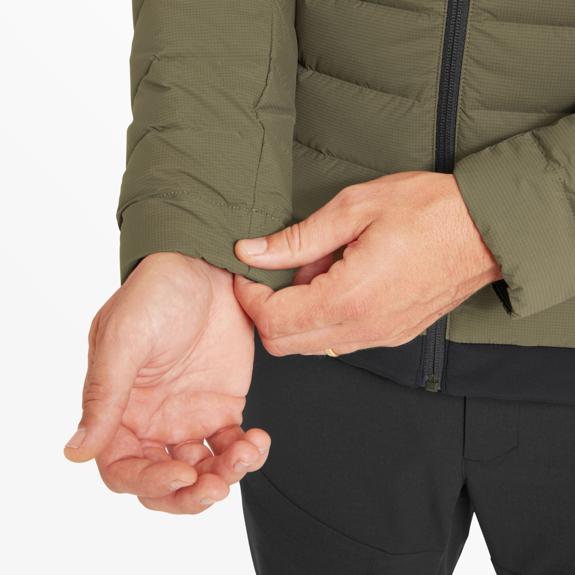 Close-up of the man's hand pulling slightly on the elasticated sleeve cuff on the Artilect Performance Mens Divide Fusion Stretch Hoodie Green. The green fabric has a textured ripstop pattern, and the cuff fits snugly around the wrist.