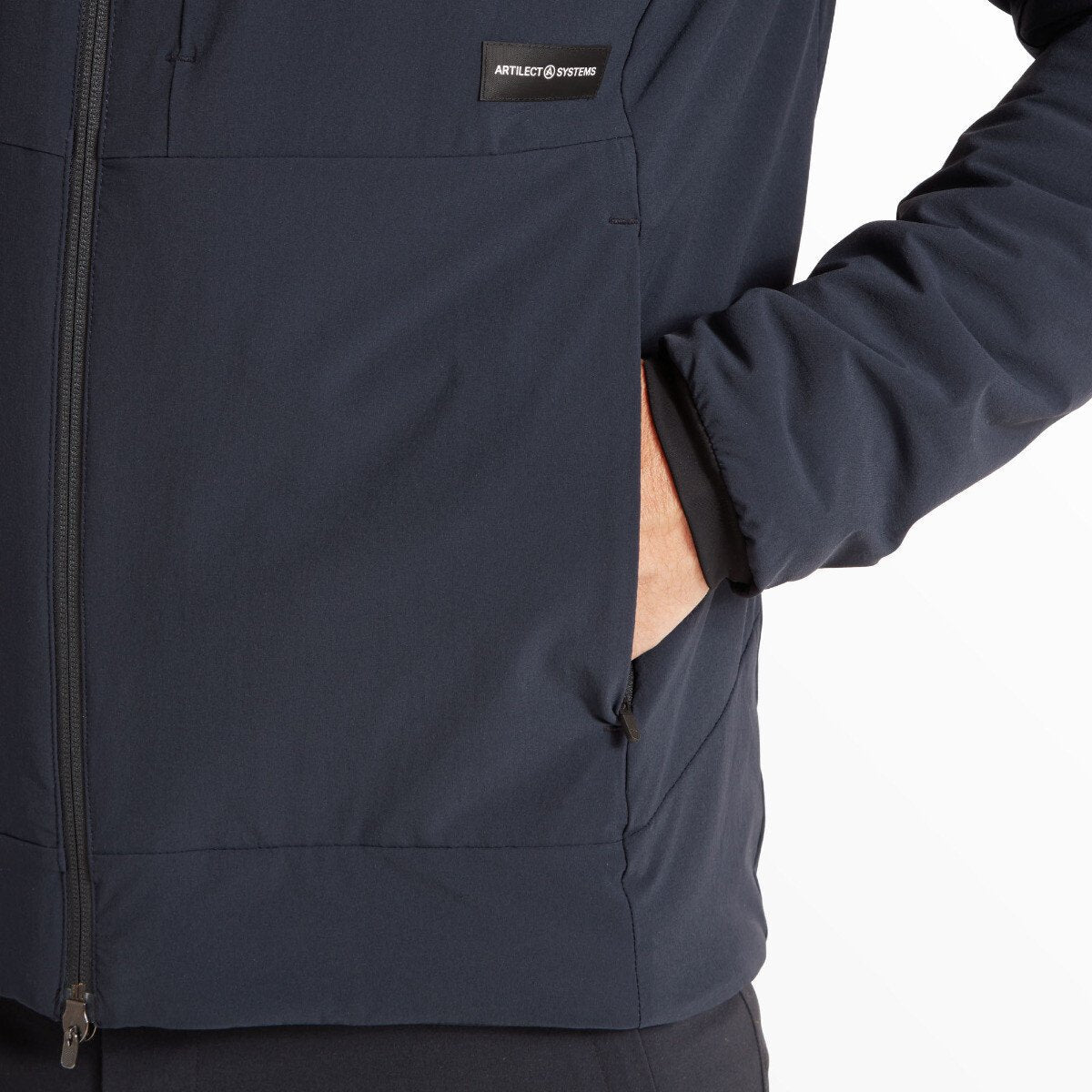 Close-up of the lower front side of the Artilect Performance Mens Elevate Primaloft Bio Insulated Hoodie Blue. The model’s hand is inserted into the side pocket, with the "Artilect Systems" logo tag displayed prominently above the seam.