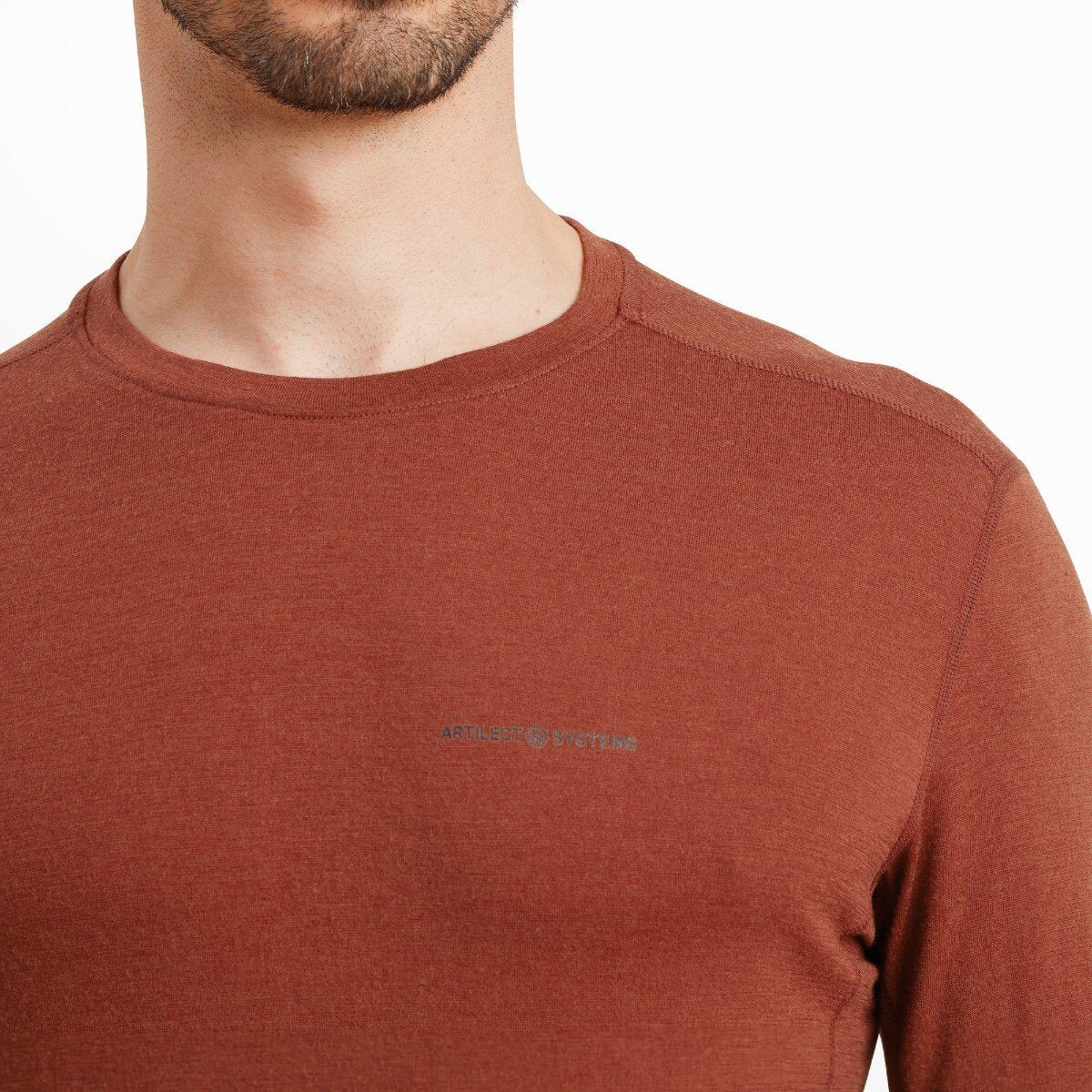 A close-up of the upper chest and neck area of the Artilect Performance Mens Exposure Long Sleeve Tee Orange. The fabric texture and stitching around the neckline are clearly visible, along with the small, subtle “ARTILECT SYSTEMS” logo printed in gray on the left chest.
