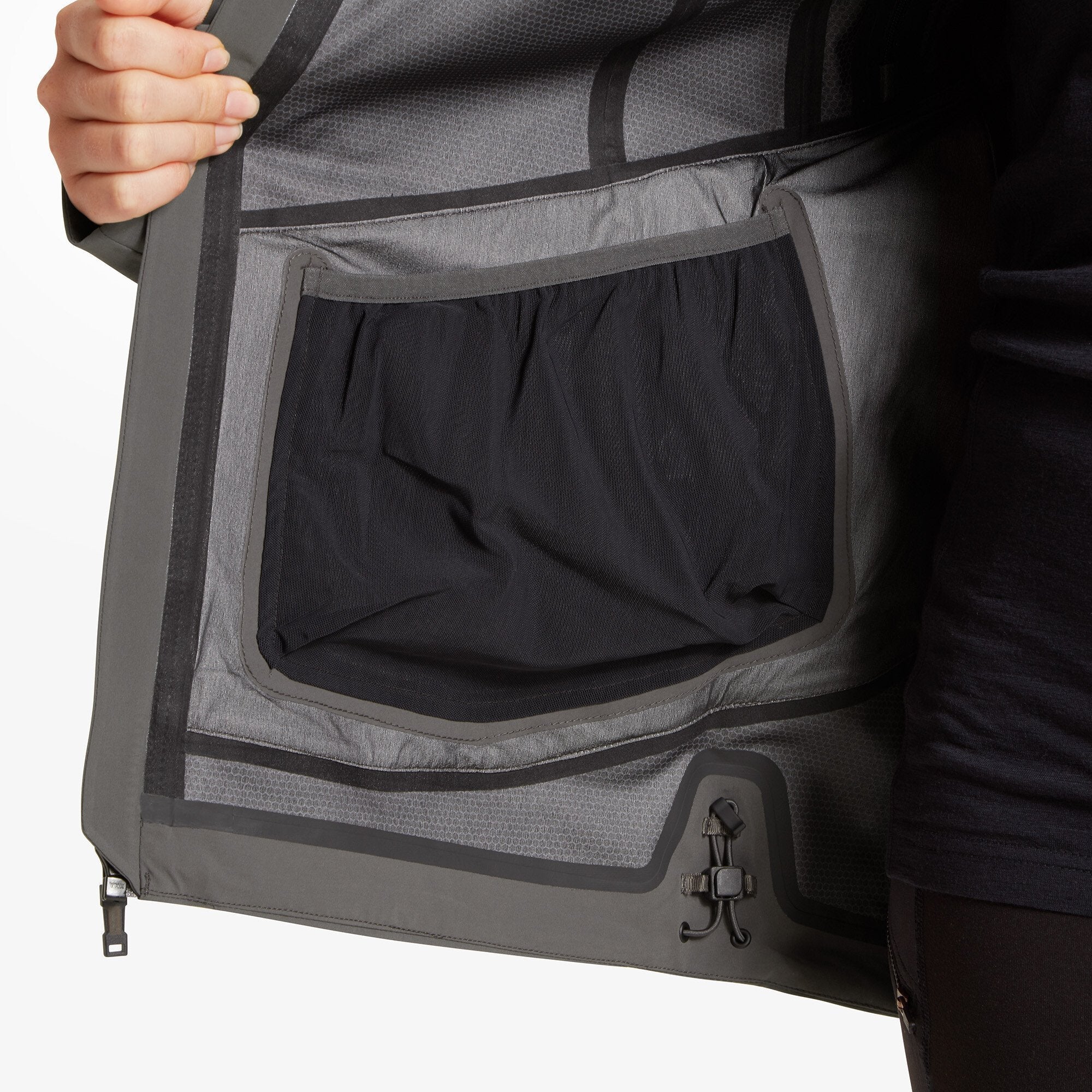 The Artilect Performance Womens Formation 3L Jacket Grey is opened to display the inside construction, featuring a mesh interior pocket and seam-sealed taping along the edges for added weather protection. A hem cinch cord with toggle is also visible.