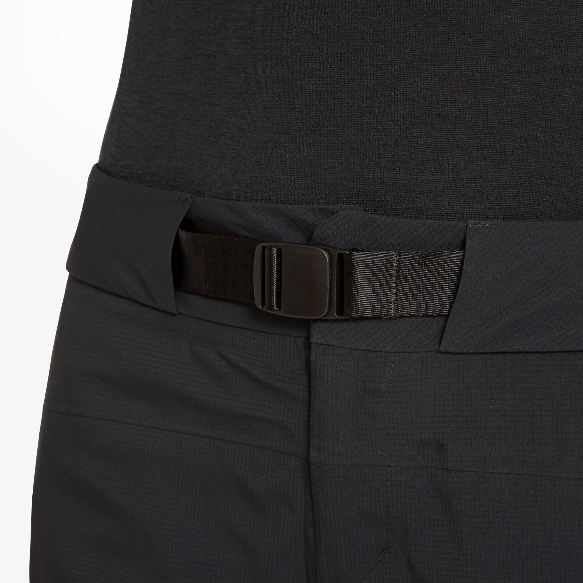 A close-up of the waistband on the Artilect Performance Womens Kinetic Pant Black, highlighting the integrated adjustable belt with a flat plastic buckle. The waistband is partially elastic and sits flat against the body, designed for secure, customizable comfort during active pursuits.