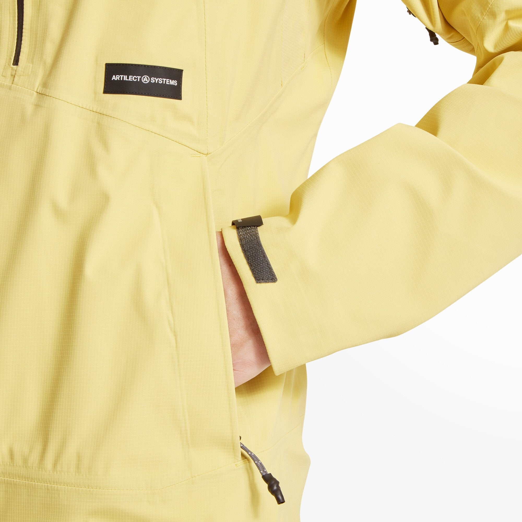 A close-up of the Artilect Performance Womens Shadow Canyon Jacket Yellow’s upper front, showing the top of the central black zipper and chest pocket zipper. The fabric gathers neatly around the collar, emphasizing the structured hood design and clean stitching.