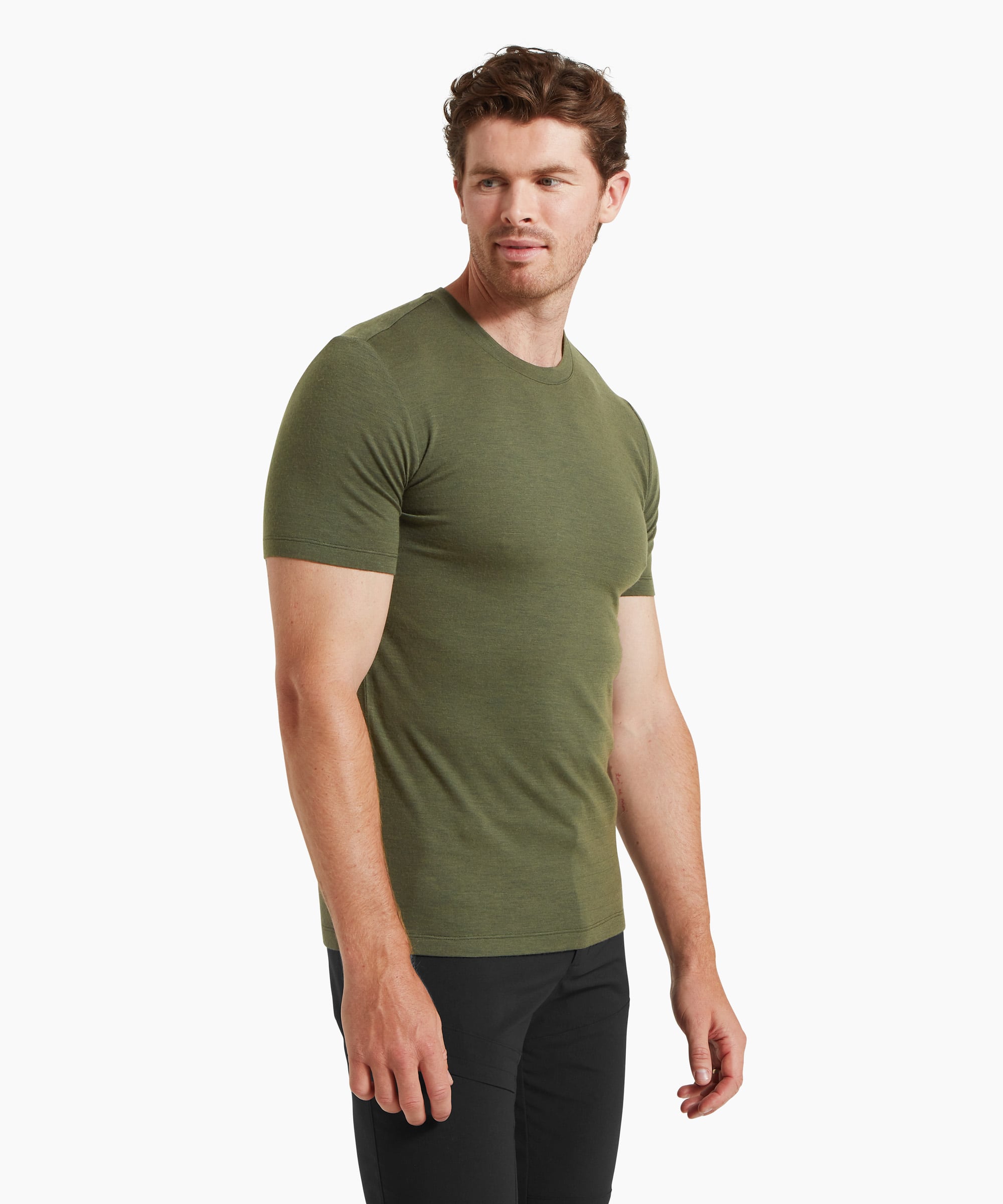 A man wearing a fitted olive-green short-sleeve T-shirt and black trousers, shown from a three‑quarter side angle against a white background.