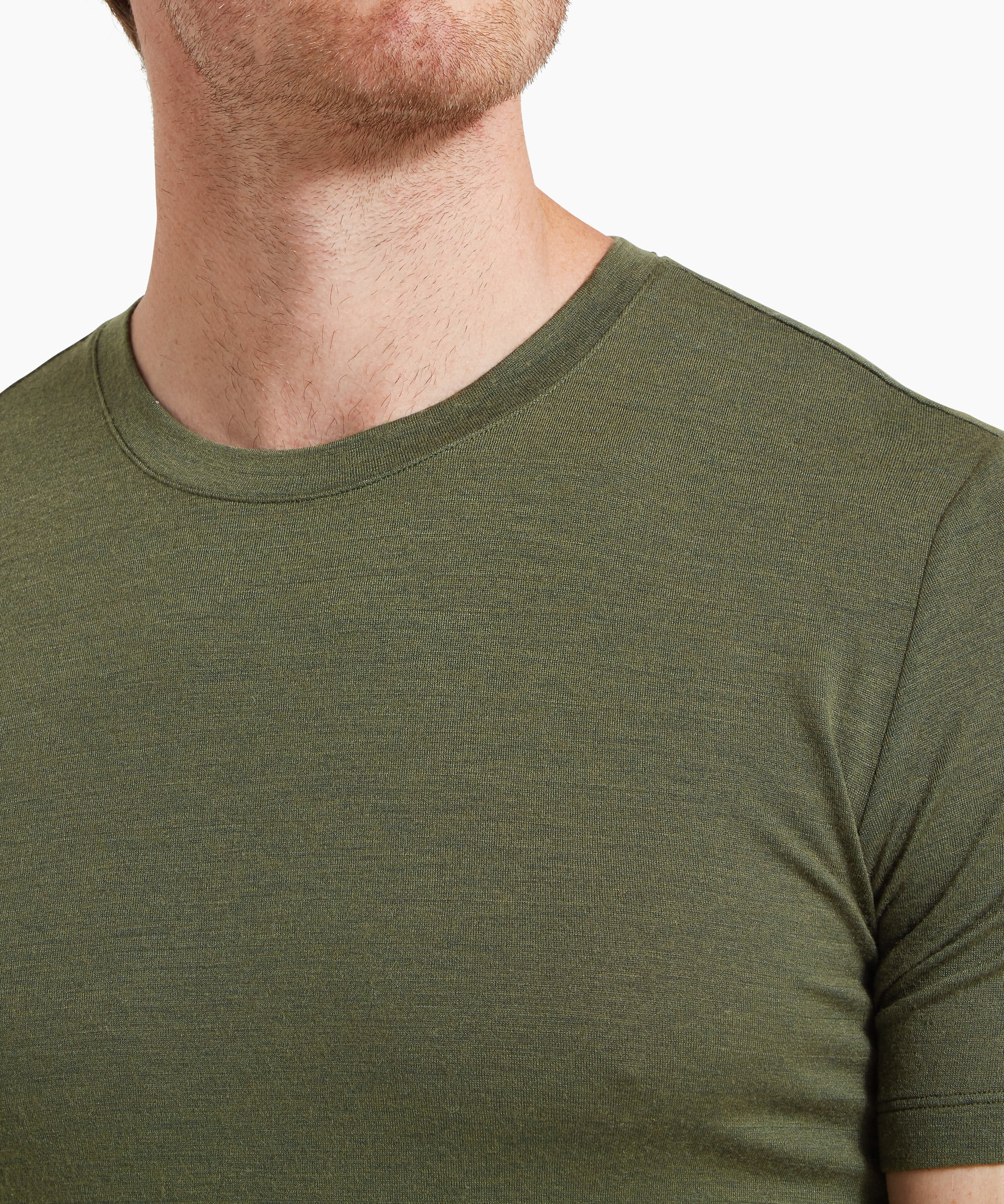 A close-up of the upper chest and neckline of an olive-green short-sleeve T-shirt, showing the ribbed crew neck and fabric texture.