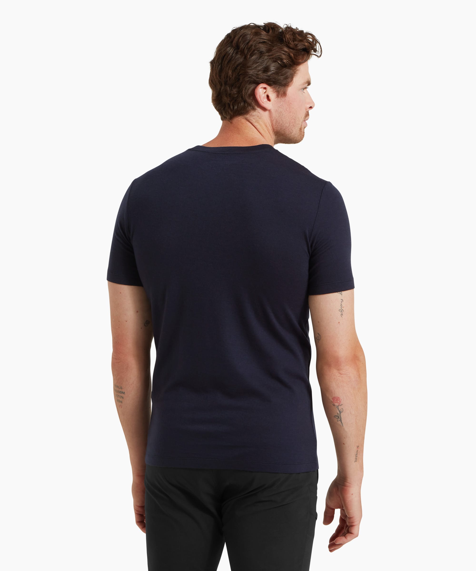 A man wearing a fitted navy short-sleeve T-shirt and black trousers, shown from the back against a white background.