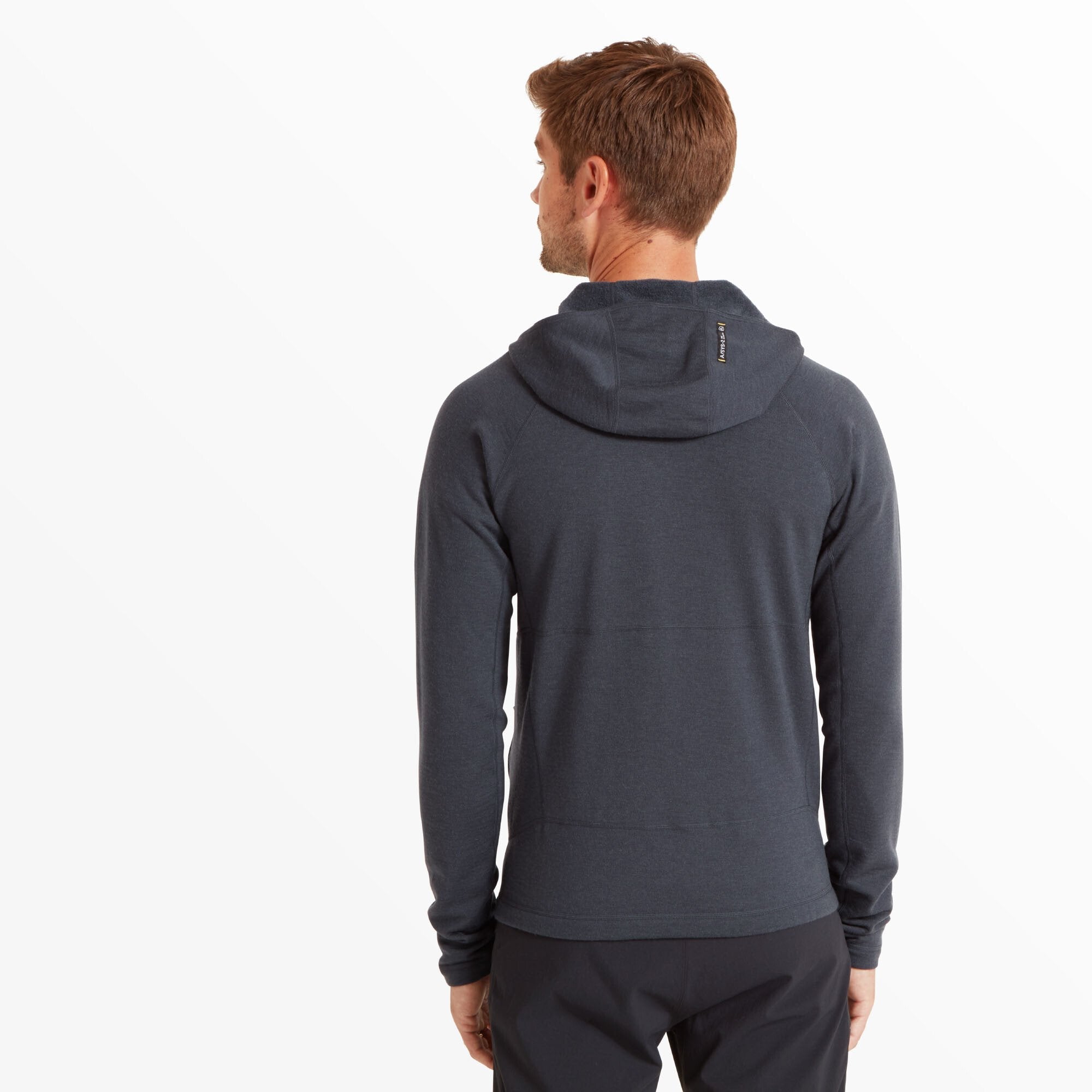 The model is facing away from the camera, showcasing the back of the Artilect Performance Mens Eldorado Merino Hoodie Blue. The hood is up, and there’s a small vertical reflective tag or label at the center back of the hood. The design is clean with minimal visible stitching.