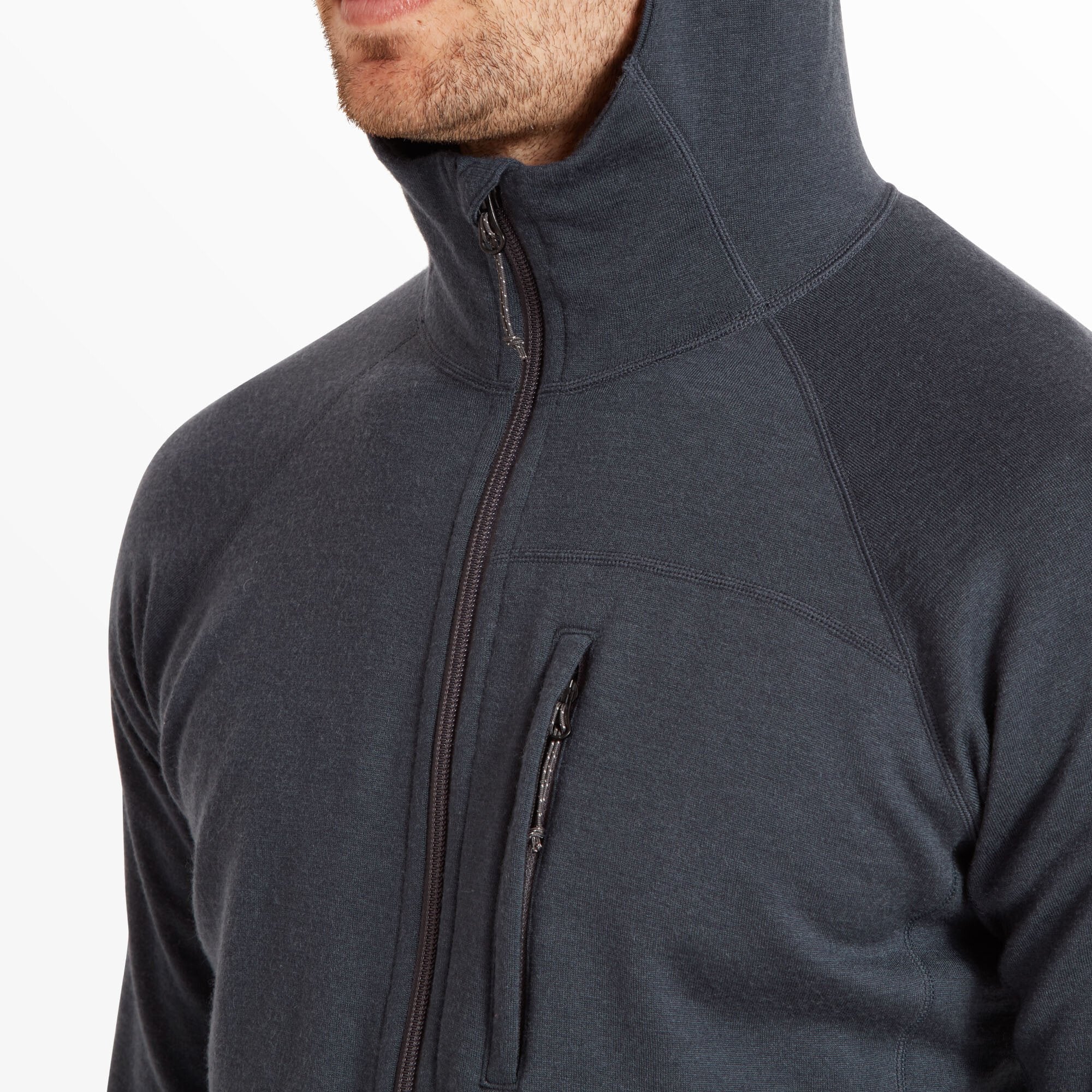 A close-up image focusing on the left chest area of the Artilect Performance Mens Eldorado Merino Hoodie Blue. The vertical zippered pocket is partially open, with a concealed zipper pull. The image highlights the fabric’s fine texture and the precision of the stitching around the pocket.
