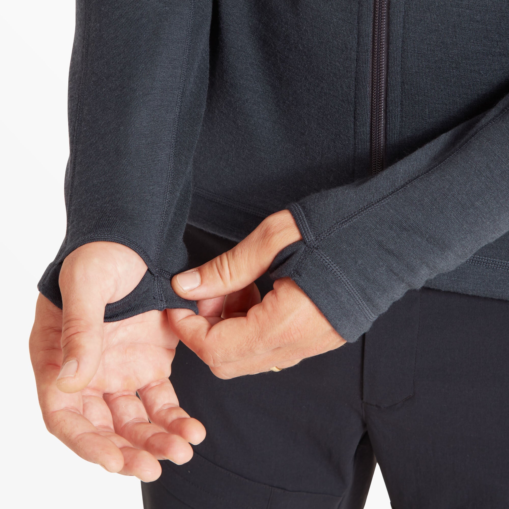 A close-up of the model’s hands as he demonstrates the integrated thumbhole feature on the sleeve cuffs on the Artilect Performance Mens Eldorado Merino Hoodie Blue. The stretch fabric fits snugly over the wrist, and the thumbholes are cleanly cut, providing extended sleeve coverage for warmth and comfort.