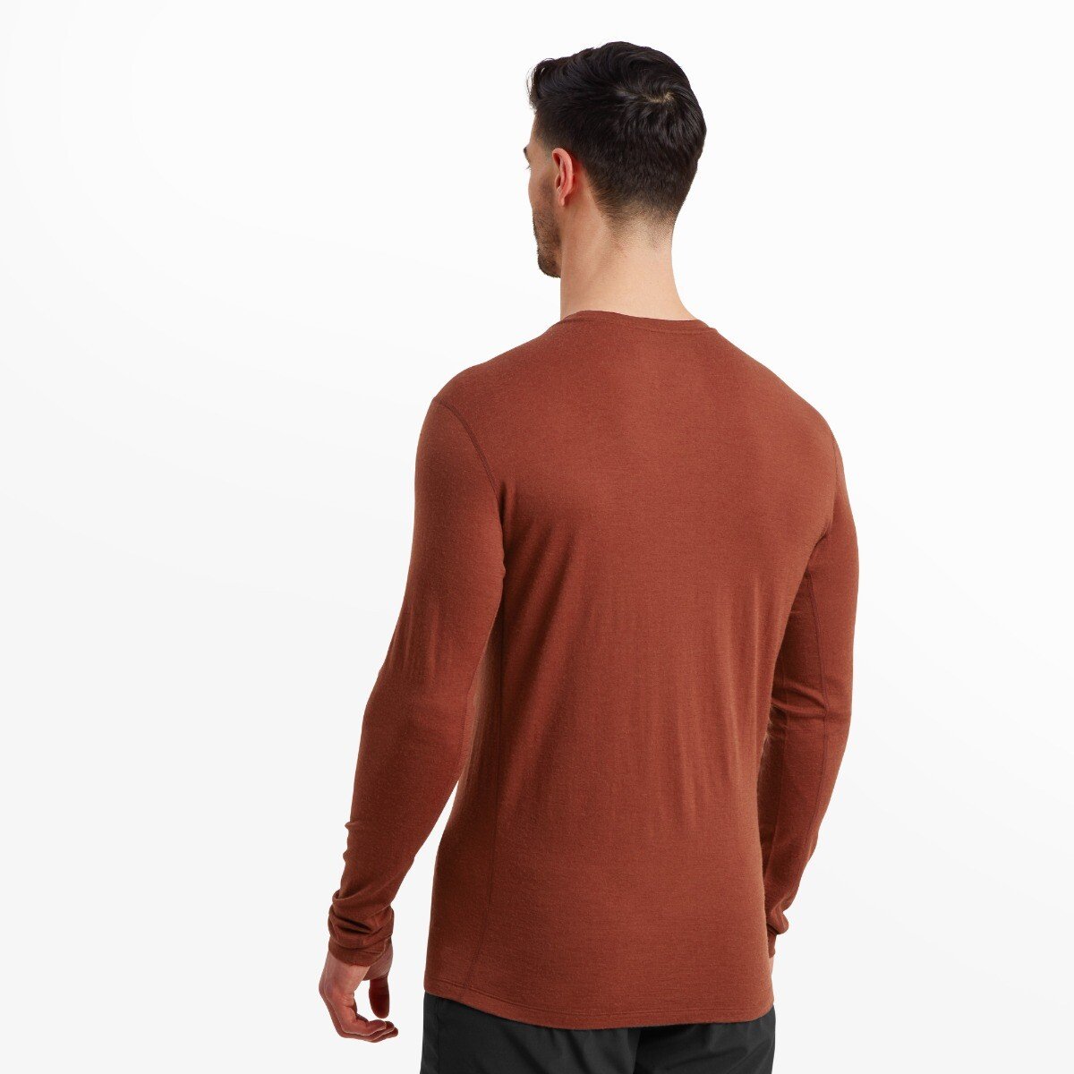 A back view of the model wearing the Artilect Performance Mens Exposure Long Sleeve Tee Orange, showing the seamless design across the back, long hemline, and snug sleeve fit. The model’s arms are relaxed, and his stance is neutral.