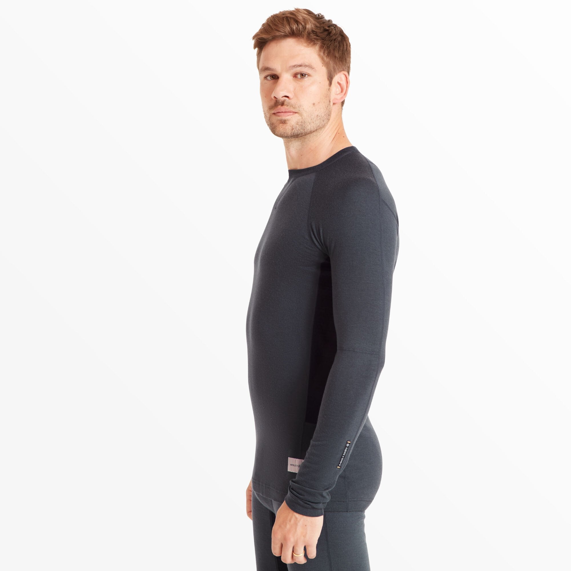 The model is turned to his left, showing the Artilect Performance Mens Flatiron 185 Crew Blue’s side profile. The slim fit and seamless design highlight the performance-oriented tailoring and underarm panels for ventilation.