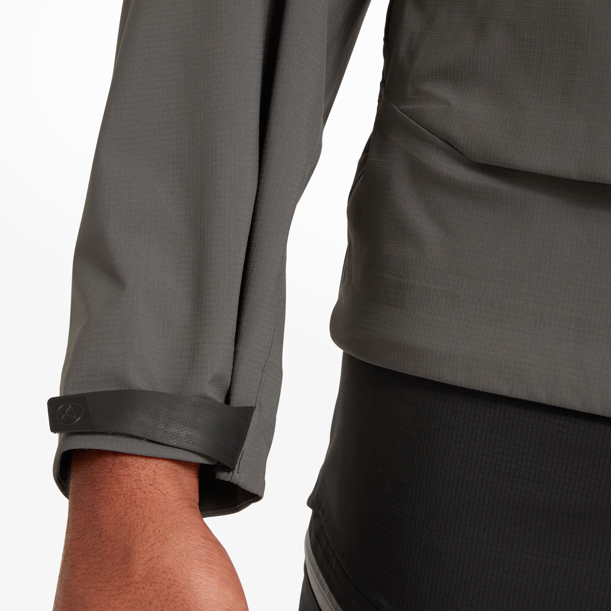 Close-up of the Artilect Performance Mens Shadow Canyon Jacket Grey's left sleeve cuff. It features a black rubberized strap with a Velcro fastener for adjusting the fit around the wrist. The stitching and material transition between cuff and sleeve are visible.