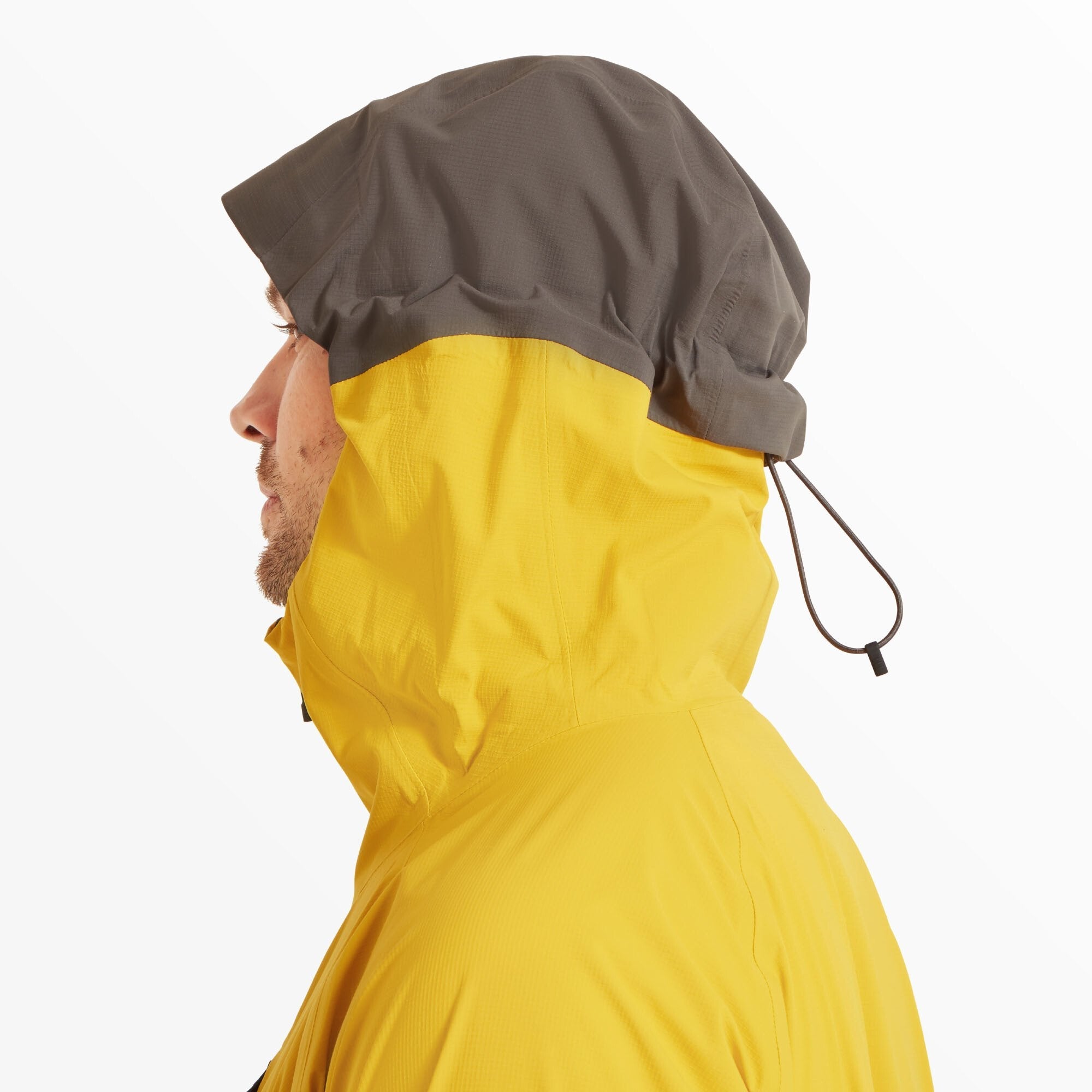 Side profile of the model wearing the hood fully up on the Artilect Performance Mens Shadow Canyon Jacket Yellow. The hood is two-toned, with a dark grey top panel and a yellow lower panel, and features an adjustable drawcord at the back for a snug fit.