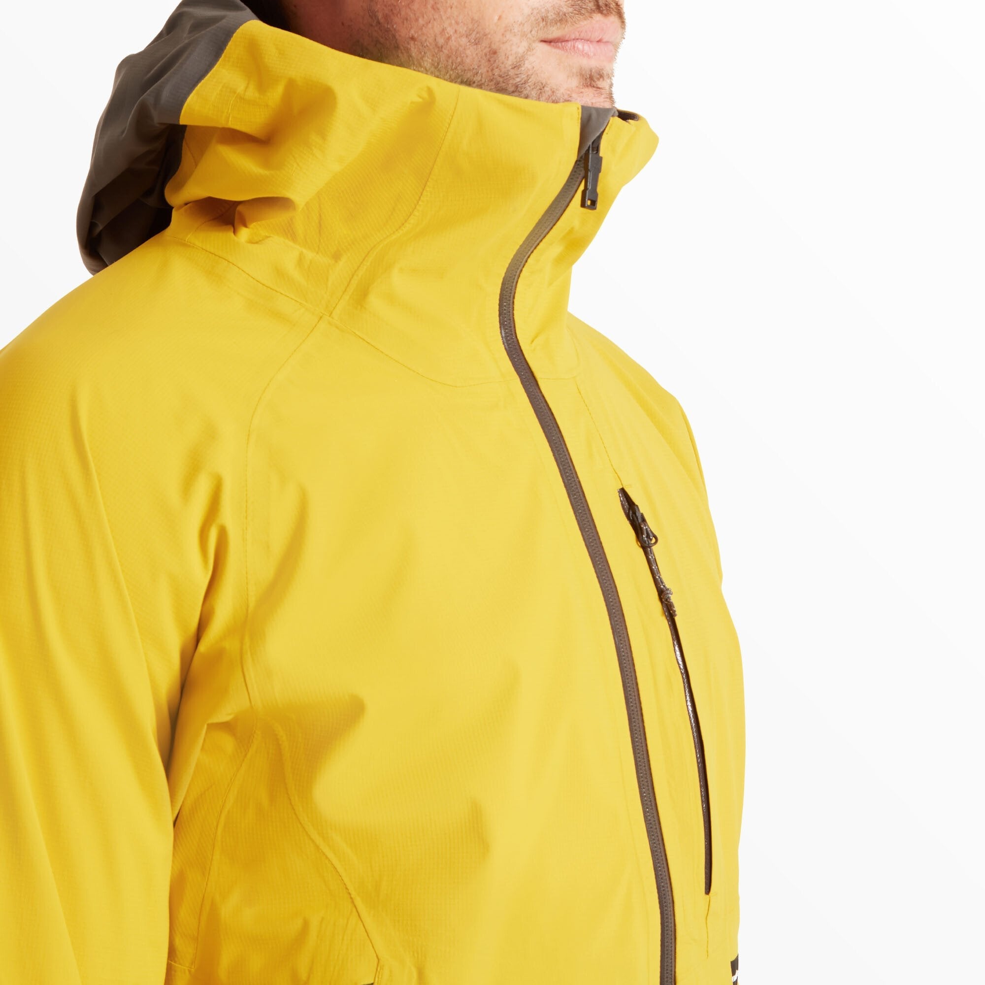 A close-up of the model’s upper chest and neck area, showing the high collar fully zipped up for weather protection on the Artilect Performance Mens Shadow Canyon Jacket Yellow. The waterproof front zip and chest pocket zip are visible, highlighting the technical seam construction.