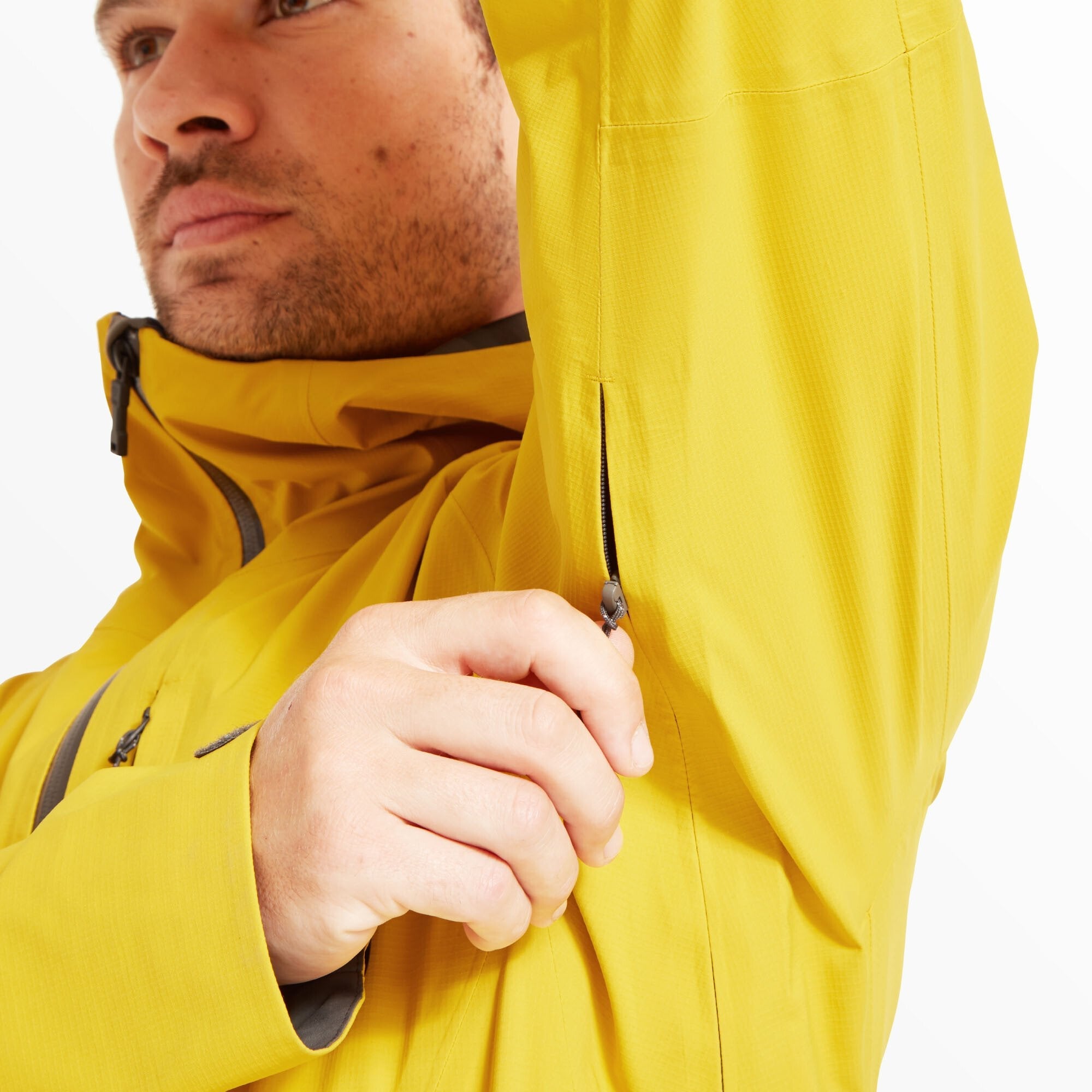 Close-up shot of the underarm area as the model opens the pit vent zipper. This feature highlights the Artilect Performance Mens Shadow Canyon Jacket Yellow’s breathability and ventilation options for active wear.