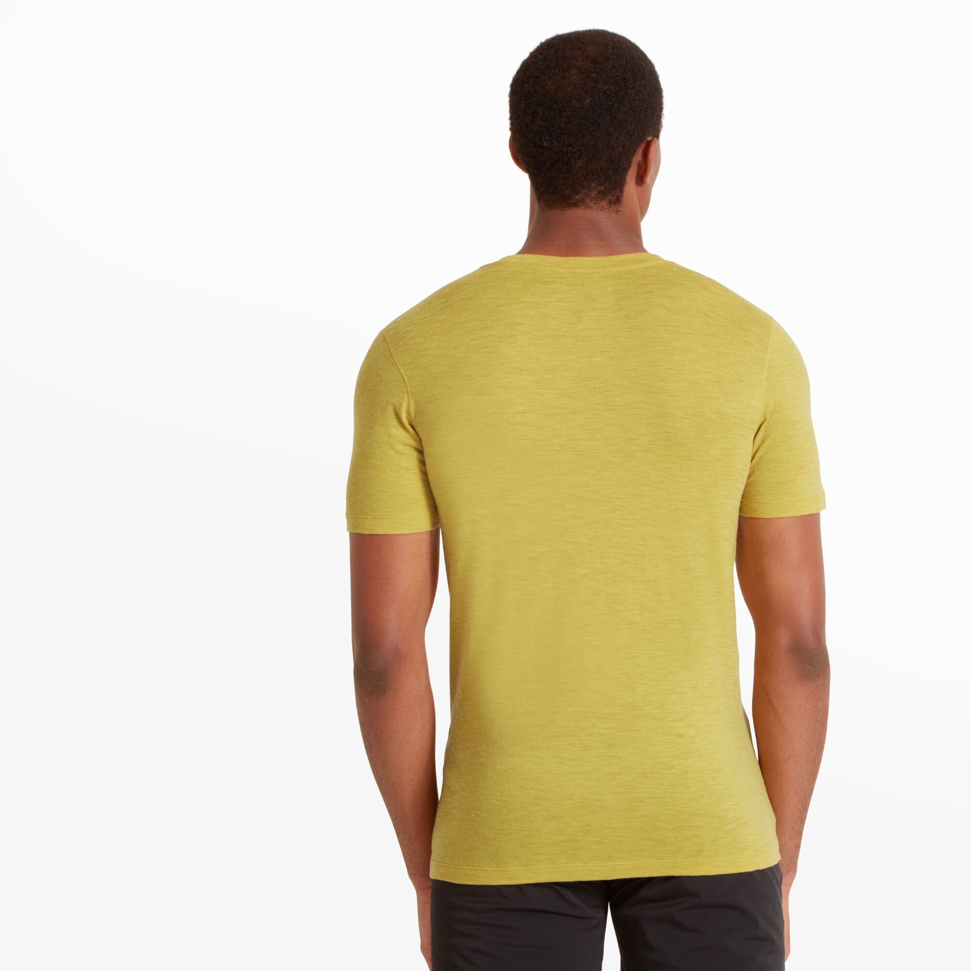 The model is seen from the back, showing the full rear view of the Artilect Performance Mens Sprint Tee Yellow. The shirt has a seamless and smooth design with no visible branding on the back. The model’s shoulders are relaxed, and the straight hem falls at a natural length over his black athletic pants.
