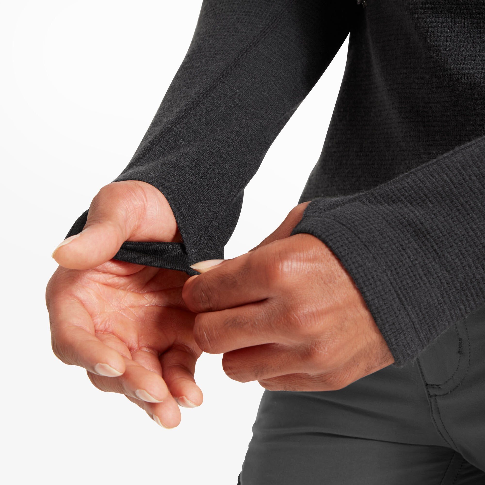Close-up of the sleeve cuff featuring a built-in thumbhole on the Artilect Performance Mens Sundown 250 Half Zip Top Black. The model is pulling the cuff over their hand, demonstrating the ergonomic design for hand coverage and warmth during cold-weather activities.