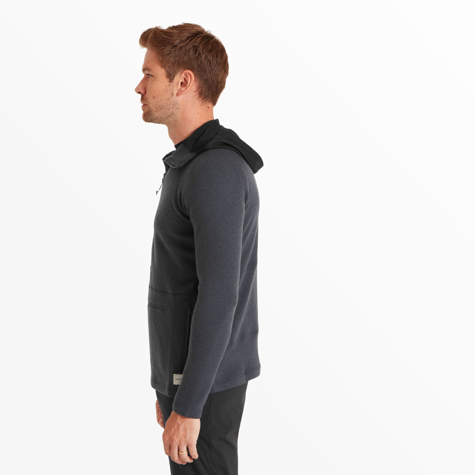 The man faces left, highlighting the slim fit and streamlined side view of the Artilect Performance Mens Sundown 250 Half Zip Top Blue. The hood lies flat against the back, and the subtle waffle-knit texture of the fabric is visible along the side torso and arm.