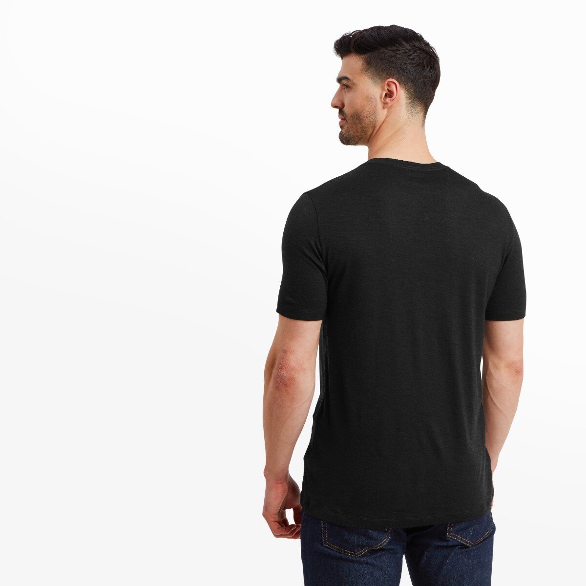 Rear view of the Artilect Performance Mens Utilitee Draft Black showing a clean, solid back with no graphics or seams. The shirt fits snugly around the model’s shoulders and arms, and he is slightly turned to the right while glancing over his shoulder.
