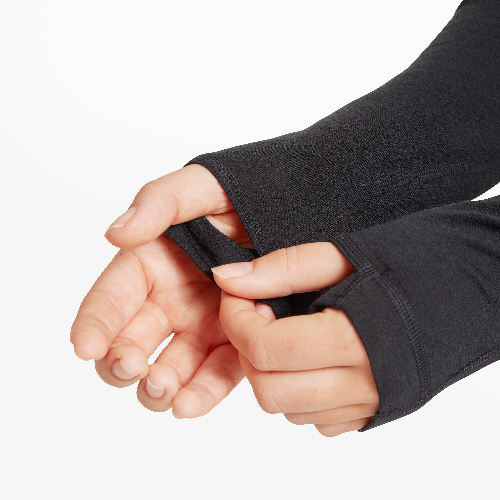 A detailed view of the model’s hands as she demonstrates the thumb holes in the Artilect Performance Womens Boulder 125 Quarter Zip Top Black. The fabric extends over part of her hands, leaving only her fingers exposed, showing how the thumbhole feature secures the sleeves in place. The material appears soft and stretchy.