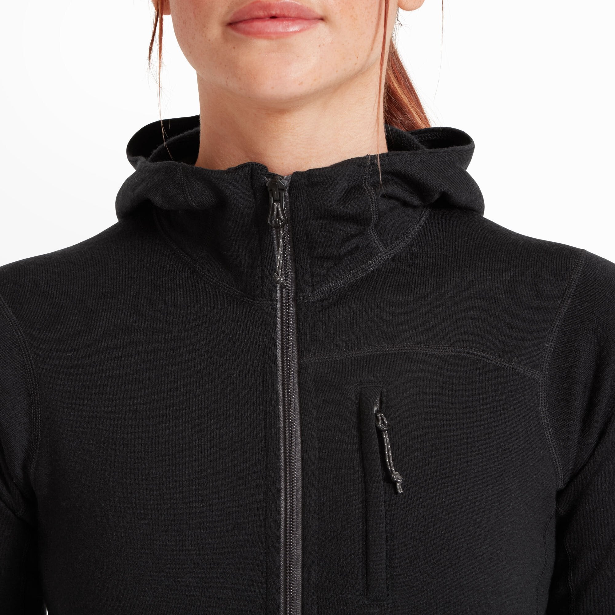 Zoomed-in view of the upper front of the Artilect Performance Womens Eldorado Merino Hoodie Black, focusing on the main zipper and the vertical chest pocket. The zippers have durable toggles, and the stitching around the collar and shoulder area shows quality craftsmanship.