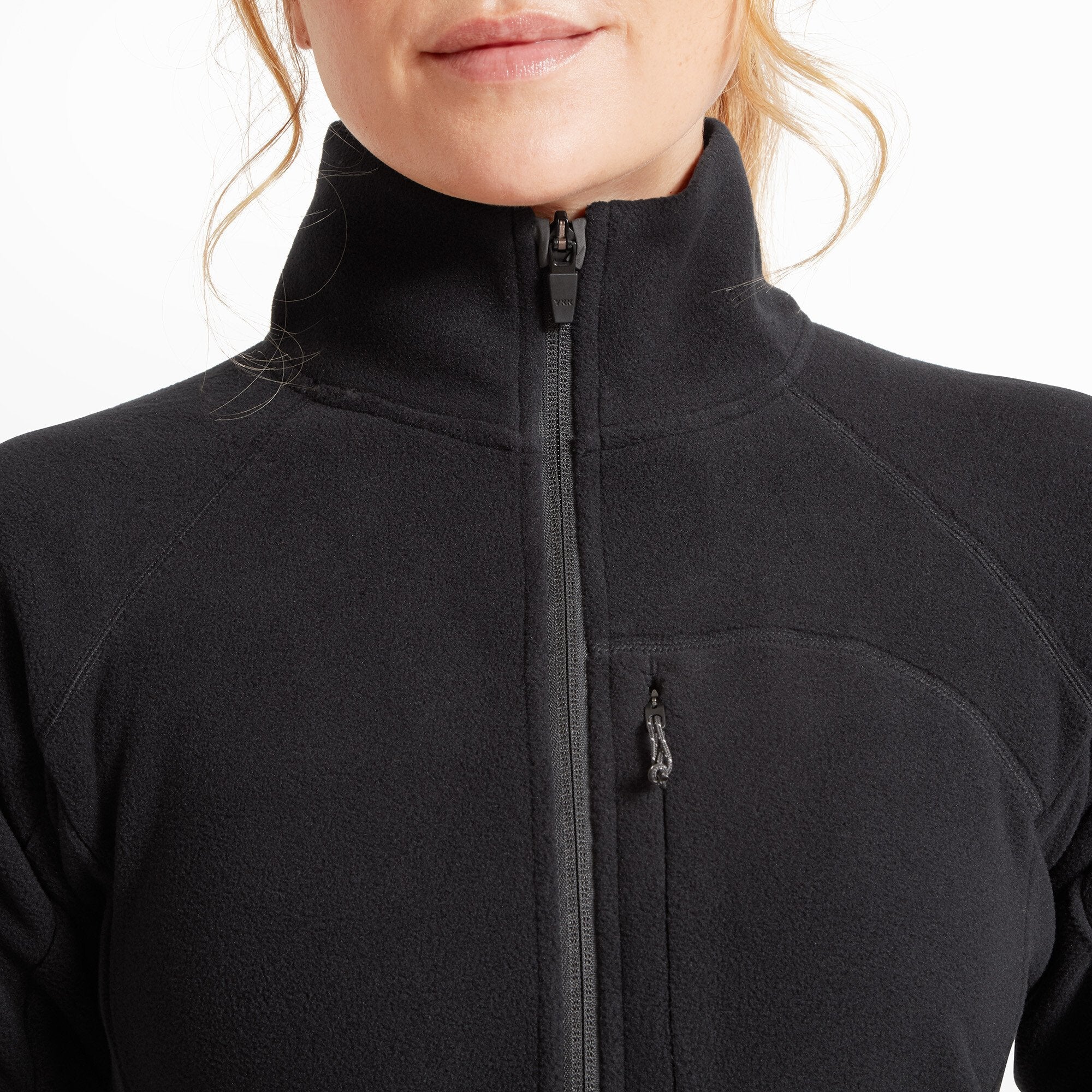 Close-up of the upper chest and neck of the Artilect Performance Womens Halfmoon Bio Pullover Black. The half-zipper is zipped to the top, showcasing the tall collar and the small chest pocket with a vertical zipper.