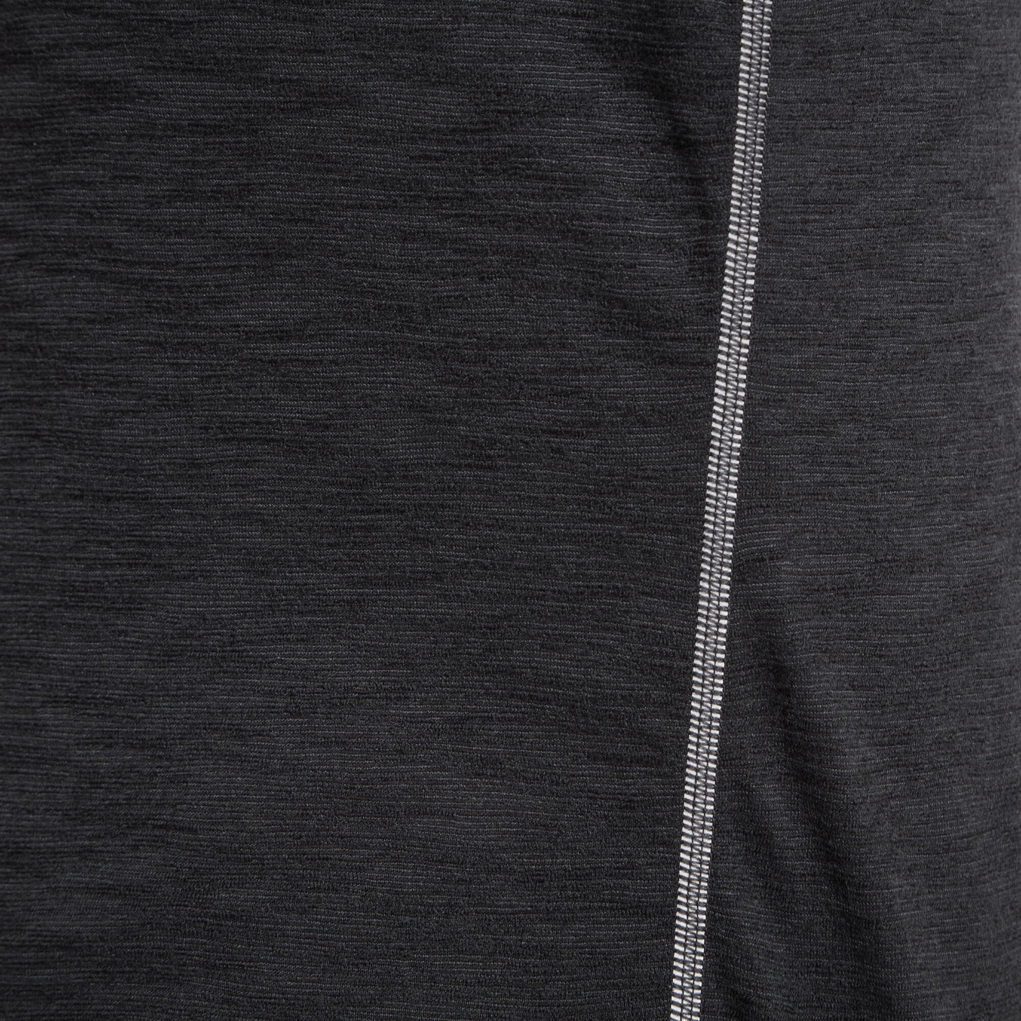 Macro close-up of the side seam of the Artilect Performance Womens Sprint Long Sleeve Tee Black, highlighting the stitching detail and fabric texture. The dark heathered black fabric has a smooth, performance-knit appearance, and the double stitching running vertically along the seam adds durability and visual interest.