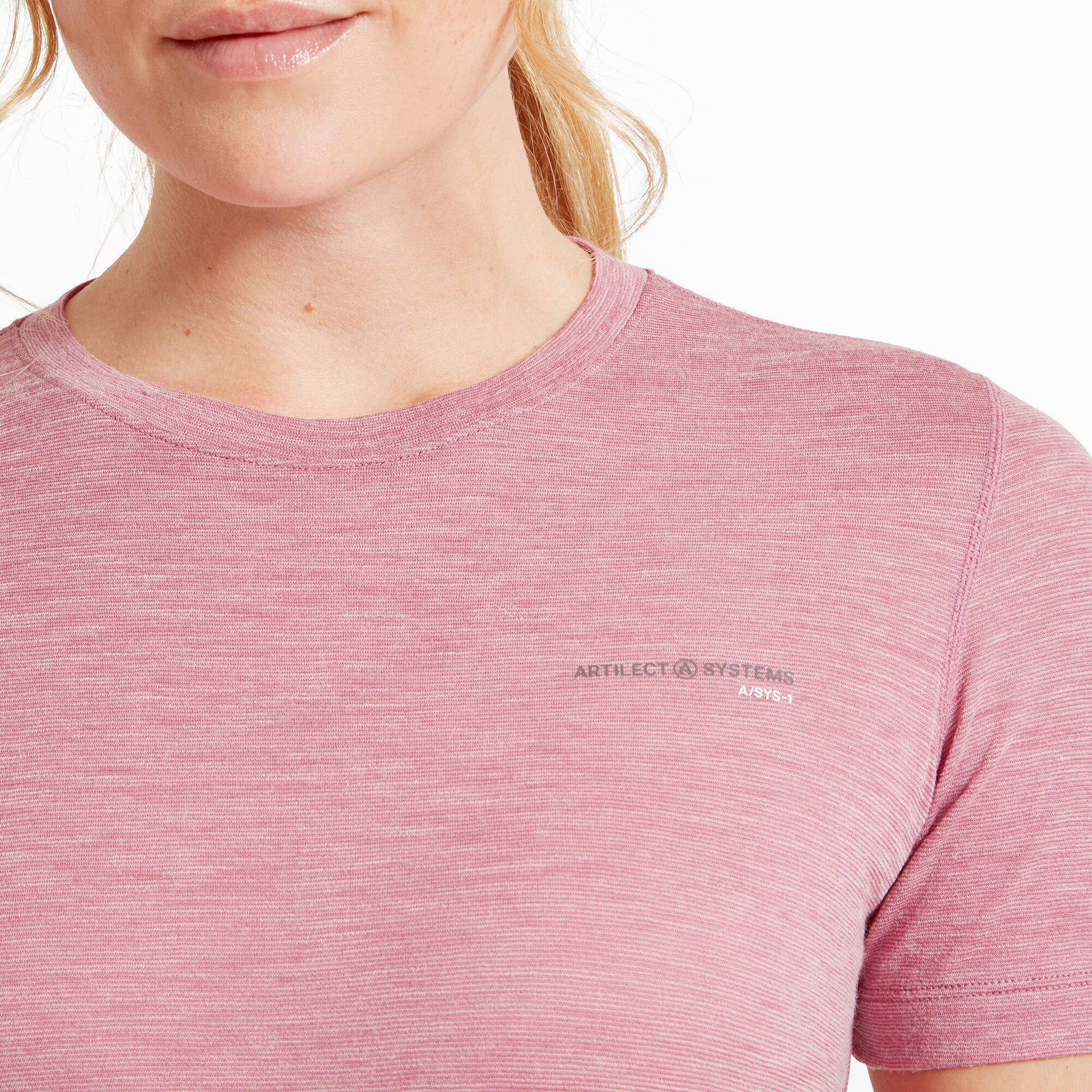 Close-up of the upper chest and neckline of the Artilect Performance Womens Sprint Tee Pink. The ribbed crew neck is shown in detail, with reinforced stitching. The logo “ARTILECT SYSTEMS A/SYS-1” is clearly visible just below the left collarbone in small, dark gray text. The fine-knit texture of the fabric is also prominent.