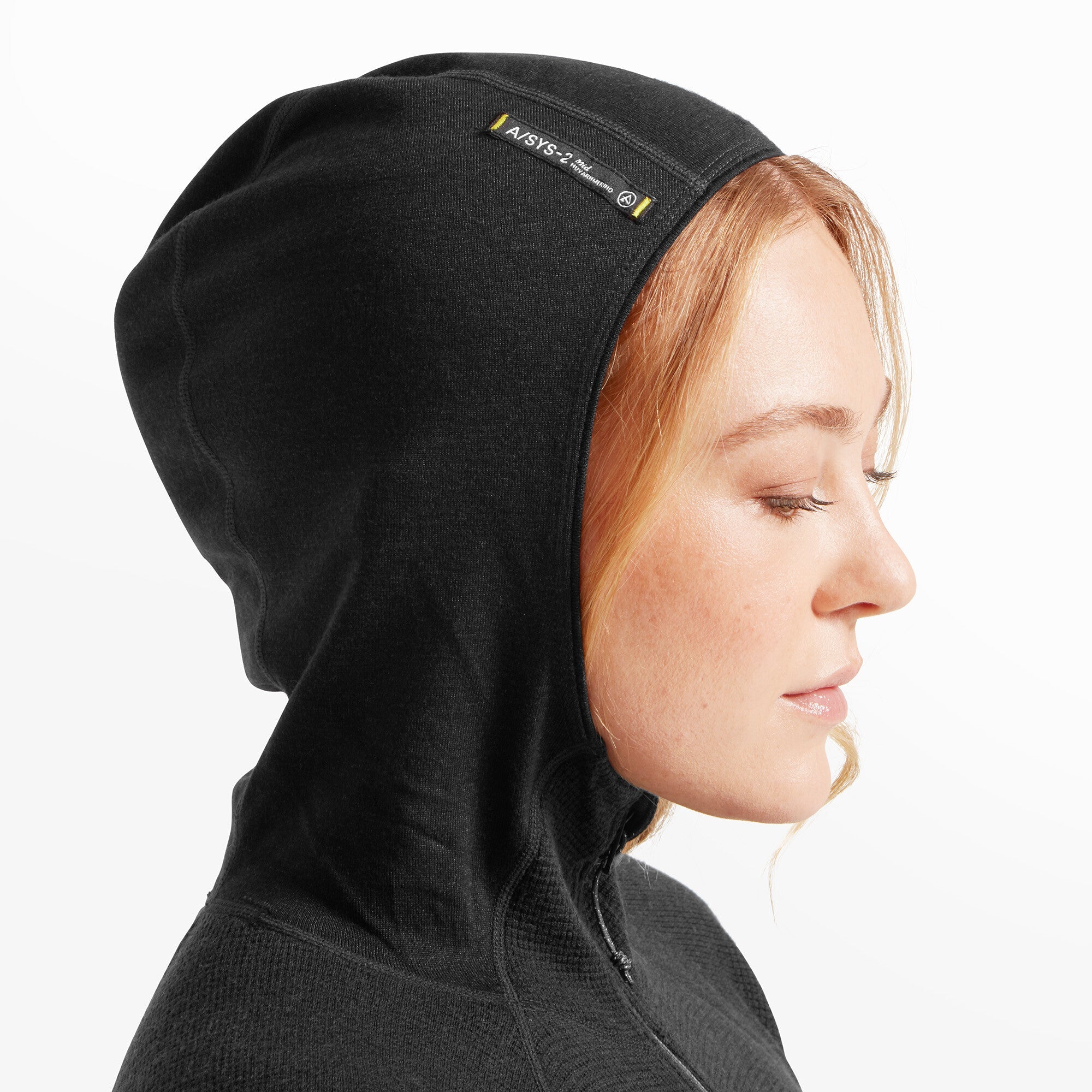 Close-up of the hood worn up on the Artilect Performance Womens Sundown 250 Half Zip Top Black, focusing on the ASYS-2 system branding stitched on the top edge of the hood in yellow and white on a black tag.