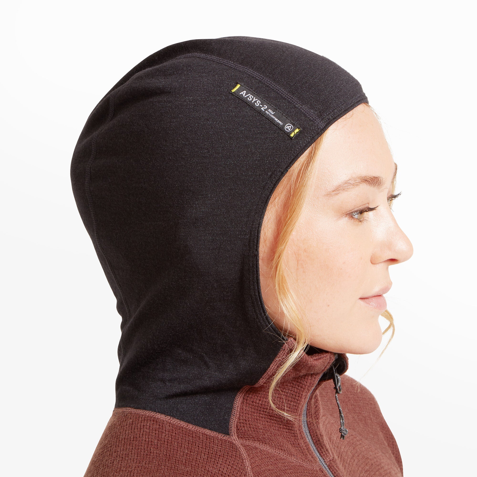 A close-up of the upper chest and neckline area of the Artilect Performance Womens Sundown 250 Half Zip Top Burgundy. The half-zipper is centered and fully zipped up to the collar. The texture of the burgundy fabric, with its grid-like pattern, is visible along with the panel seams and black hood peeking from the back.