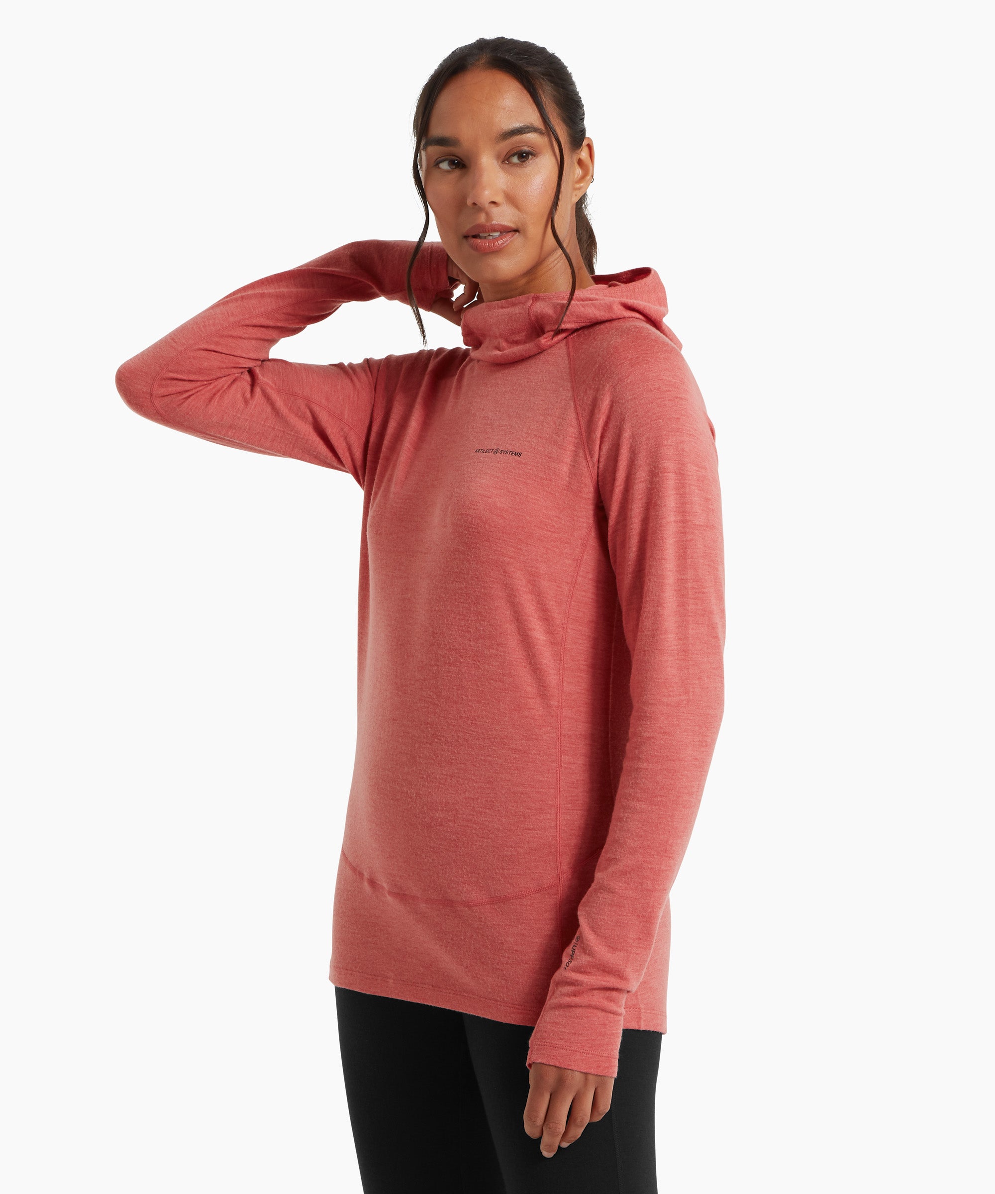 A woman wearing a coral‑pink lightweight hooded top and black leggings, shown from a three‑quarter side angle against a white background, with one hand resting behind her neck.