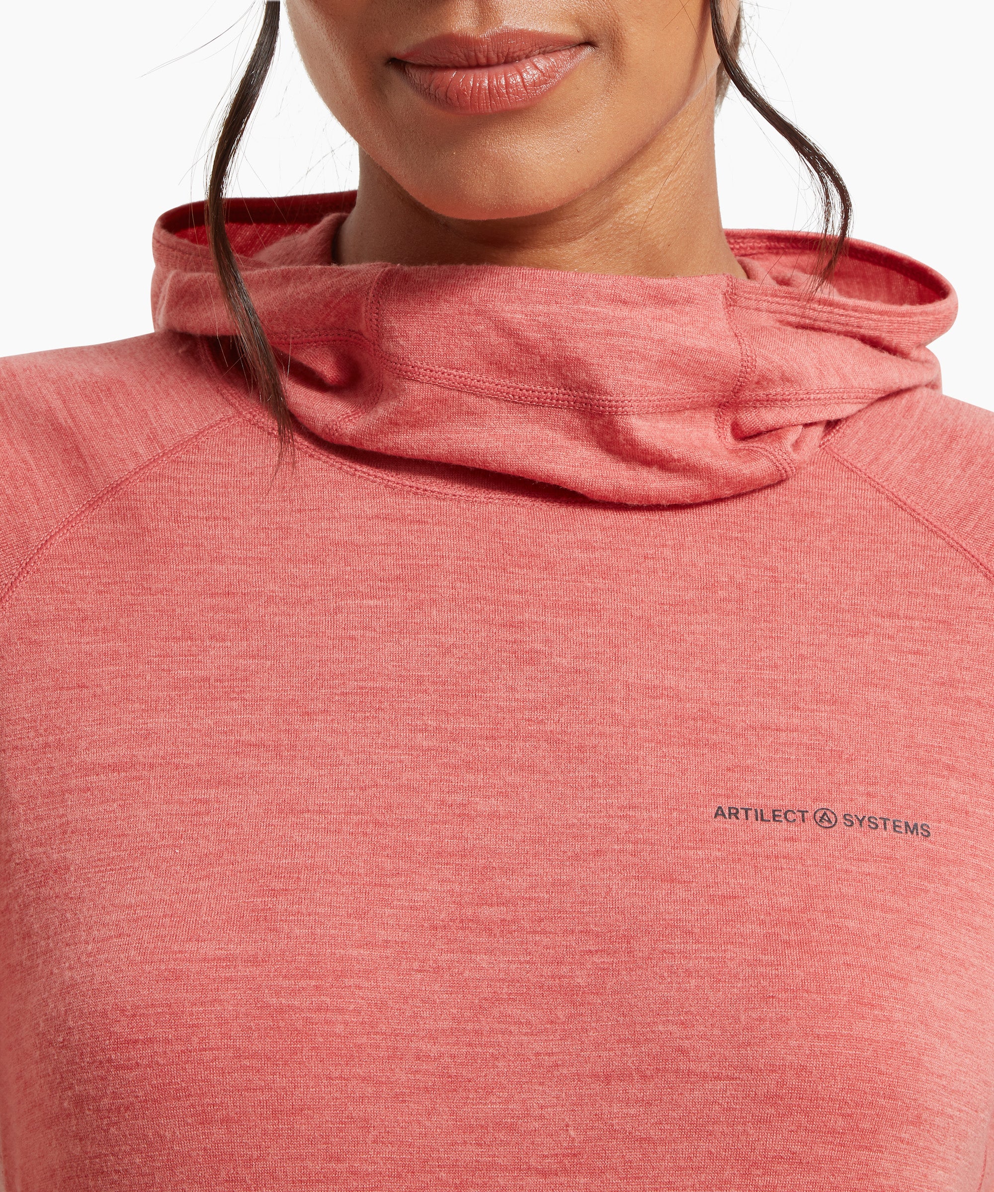 A close-up of the neckline and hood of a coral‑pink lightweight hooded top, showing the relaxed cowl-style hood and the small ARTILECT SYSTEMS logo on the left chest.